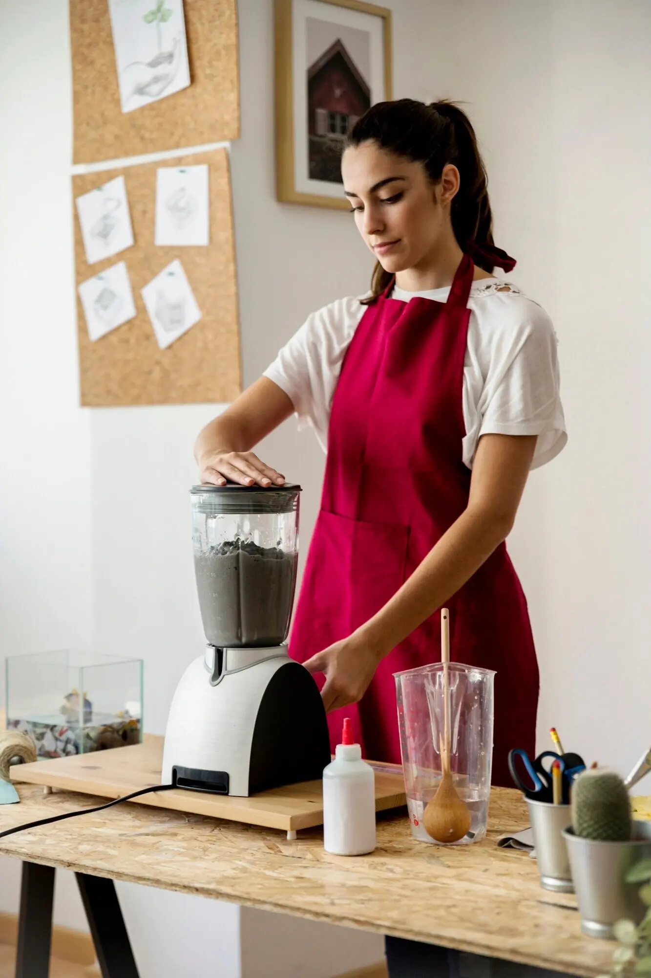 Eine junge Frau zermahlt Papierbrei in einem Mixer.