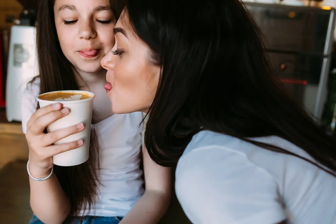 Zwei Mädchen sitzen mit einer Tasse Kaffee.